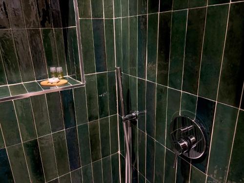 a green tiled bathroom with a shower with a toilet at Edera Rooms in Tolfa
