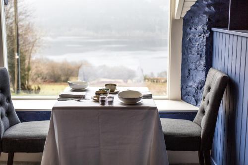 The Inn at Loch Tummel في Tummel Bridge: طاولة و كرسيين مع طاولة و نافذة