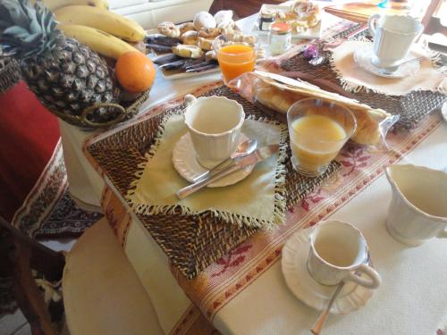 a table with cups and plates of food and fruit at B&B Mare E Natura in Cuile Ezi Mannu