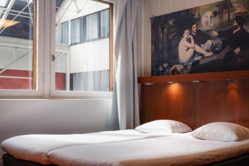 a bed in a room with a painting on the wall at Omena Hotel Helsinki City Centre in Helsinki