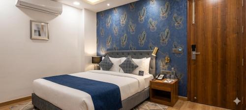 a bedroom with a bed and a blue wall at Hotel Aroha Stayz At Sector 44 Noida in Noida