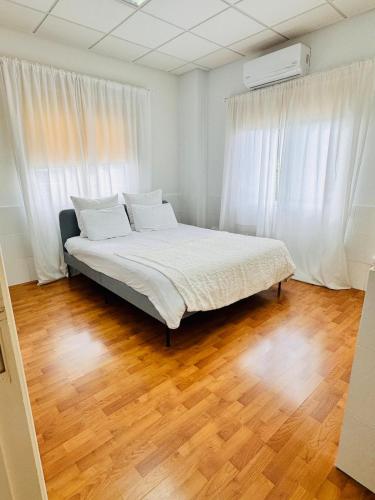 a bed in a room with white curtains and wooden floors at Stylish Apartment with Spacious Terrace in Aglantzia
