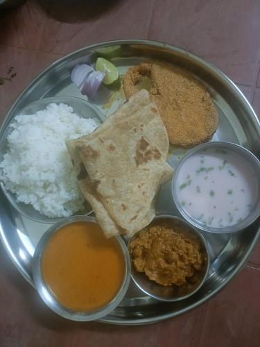 a plate of food with rice and other food items at Vitthal prema nivas in Sawantwadi