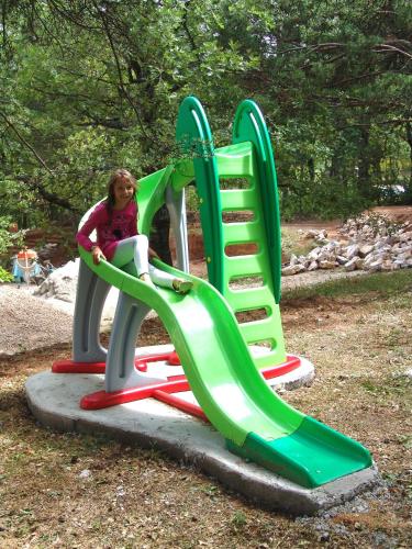 a young girl sitting on a slide at a playground at Appartement T2 "Altaïr" de l'observatoire in Bauduen