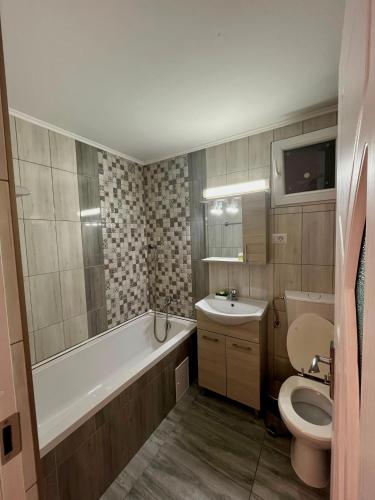 a bathroom with a tub and a toilet and a sink at Calypso Rooms in Făgăraş