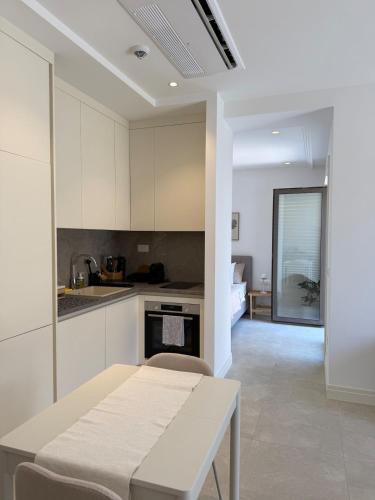 a kitchen with white cabinets and a table at Charming studio-plus in Lustica Bay Centrale in Radovici