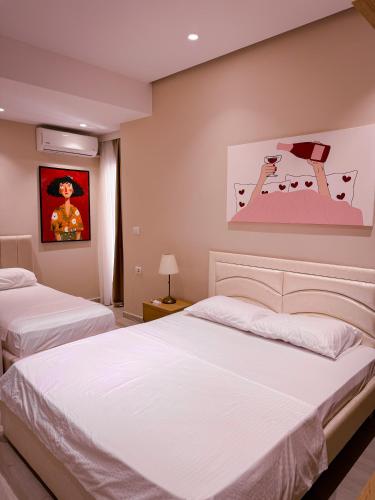 a bedroom with two beds and a painting on the wall at Lost At Sea 2 in Sarandë