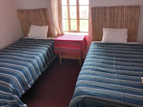 a room with two beds and a chair and a window at Hospedaje jatari in Estanciasuyo