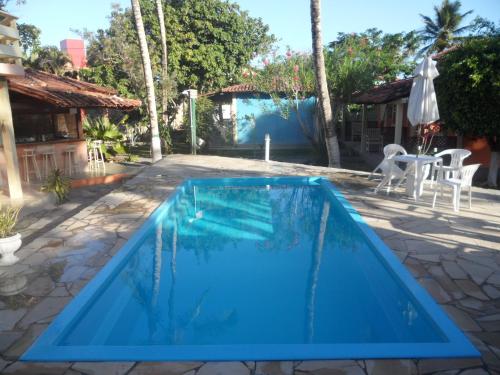 una piscina azul en un patio con mesa y sillas en Hotel Pousada Castanheiras do Village, en Porto Seguro