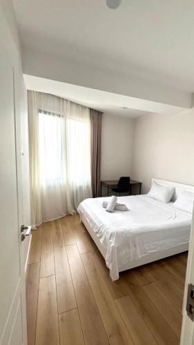 a bedroom with a white bed and a wooden floor at 21 floor apartment in Tbilisi City