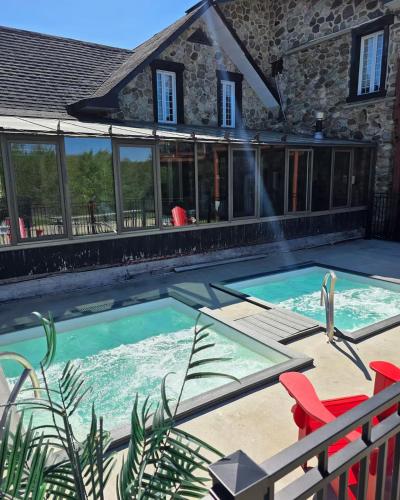 a swimming pool with red chairs and a house at L'escale d'Orford in Orford