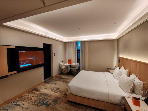 a hotel room with a bed and a flat screen tv at Ayas Hail Hotel - فندق أياس حائل in Hail
