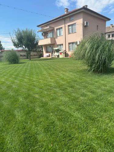 a large grassy yard in front of a house at Къща Бети самостоятелни апартаменти с двор край Пловдив in Skutare