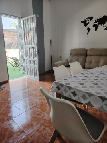 a dining room with a table and chairs and a couch at Casa adosada con patio in Jerez