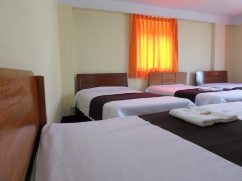 a room with four beds and a window at Hostal Casa del Montañista in Huaraz