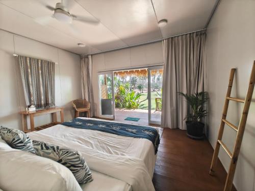 a bedroom with two beds and a large window at Sumba Retreat Kerewe in Waikabubak