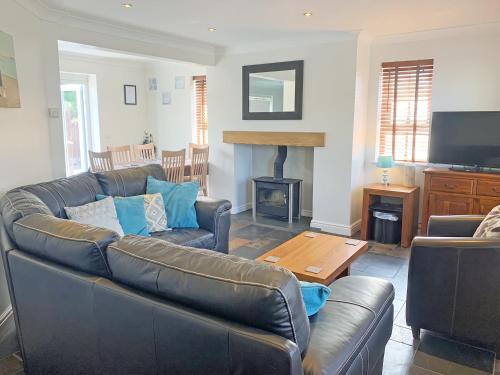 a living room with a leather couch and a table at Ty Ffynnon - Hw7601 in Llansantffraid
