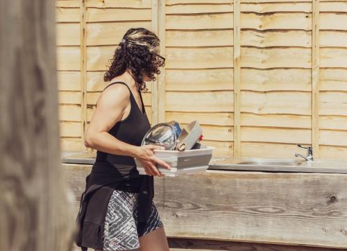 a woman is holding a box of dishes at Leto Shepherds Hut By Airpremier in Alfriston
