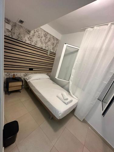 a small bedroom with a bed and a window at Hostal Alegria Alicante in Alicante
