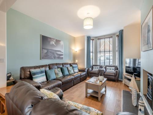 a living room with a leather couch and a tv at Samphire in Bacton