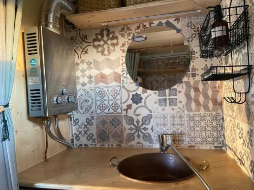 a kitchen with a sink and a mirror on the wall at Tiny ou Petite maison sur roulettes in Le Fay