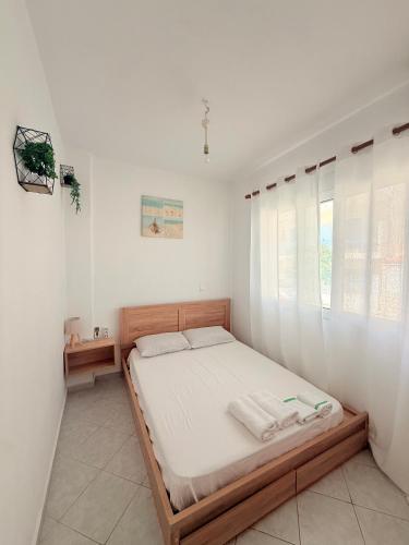 a bedroom with a bed with white walls and a window at FLISVOs 70 m από την θάλασσα in Erateini