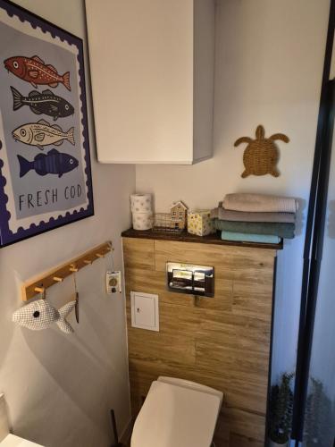 a bathroom with a toilet and a fish sign on the wall at Ustka- Wakacyjny Domek Letni Wiatr in Ustka