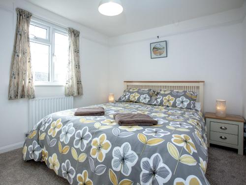 a bedroom with a bed with a blue and yellow bedspread at Garden Cottage in Kingsbridge