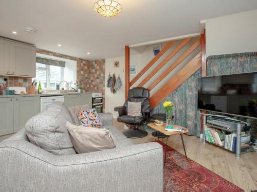 a living room with a couch and a kitchen at Garden Cottage in Kingsbridge