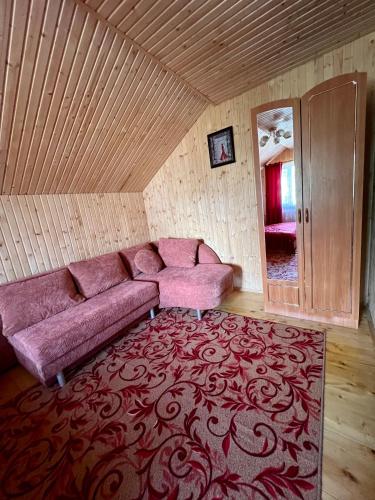 a living room with a couch and a red rug at Котедж Amber in Mykulychyn