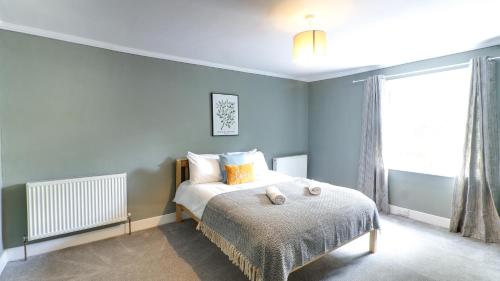 a bedroom with a bed with blue walls and a window at Delightful Durham Home in Gilesgate