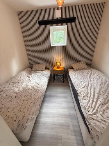 a bedroom with two beds and a table with a lamp at Hindås Lakeside Cabin 4 in Hindås