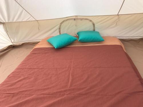 a bed in a tent with two blue pillows at GLaMPLIFE,tünni ja suitsusaunaga in Kasaritsa