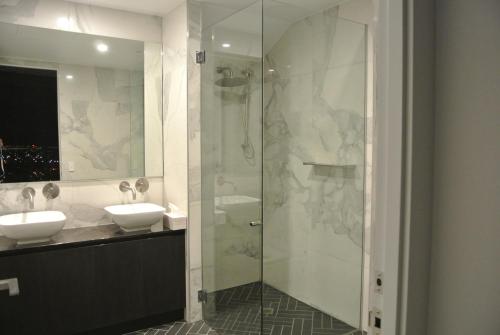 a bathroom with two sinks and a glass shower at VUE Penthouse on King William in Adelaide