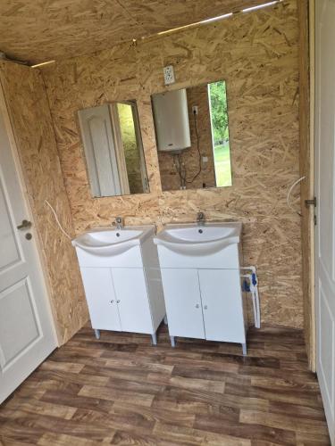 two sinks in a bathroom with two mirrors at Pura Vida Mountain Glamping-tiny houses and tents in Moieciu de Jos