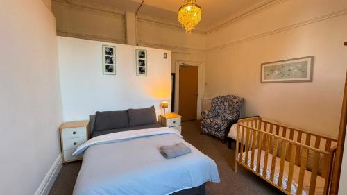 a small bedroom with a crib and a chair at Spacious Triple Studio Room, Private En-Suite & Kitchenette R6 in Sketty