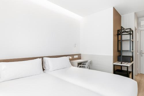 a bedroom with a white bed and a book shelf at B&B HOTEL A Coruña Aeropuerto in Culleredo