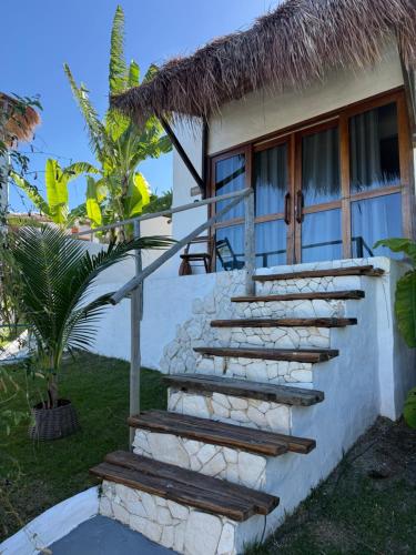 a staircase leading to a house with a thatch roof at Araxá Milagres in São Miguel dos Milagres
