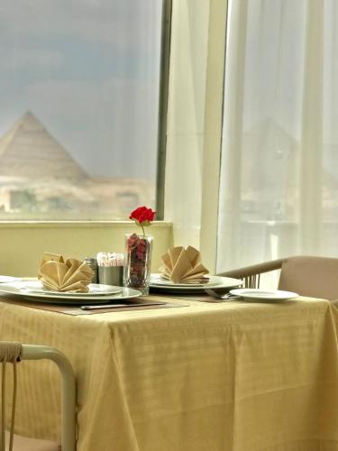 a table with two plates and a red flower on it at Pyramids view M in Cairo