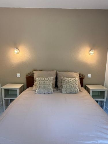 a bed with two pillows on it with two tables at Pavillon Le Luc in Ozillac