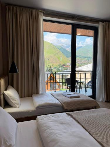 two beds in a hotel room with a large window at Hotel Sweet Night in Kazbegi