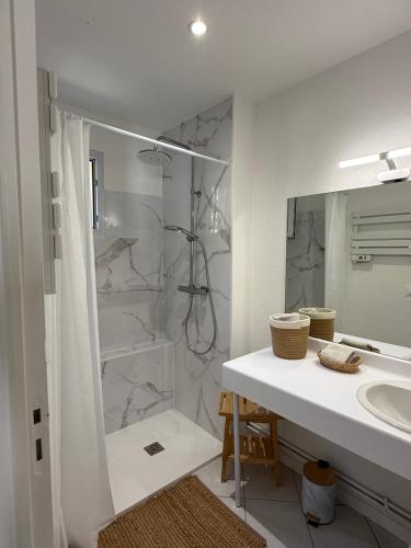 a white bathroom with a shower and a sink at Pavillon Le Luc in Ozillac