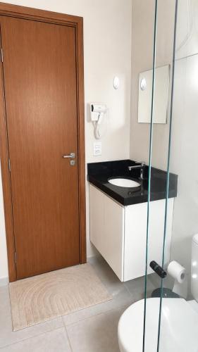 a bathroom with a sink and a wooden door at Apartamento Aconchegante de 02 Quartos in Cuiabá