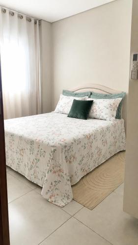 a bedroom with a bed with a white blanket and pillows at Apartamento Aconchegante de 02 Quartos in Cuiabá