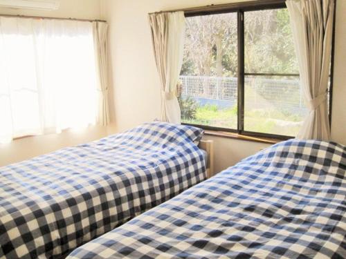two beds sitting next to a window in a bedroom at Kitchen Garden in Tateyama