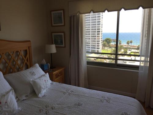 a bedroom with a bed and a large window at Apartamento Edificio Genova in Viña del Mar