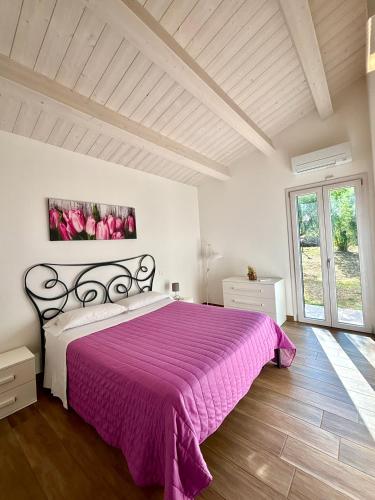 ein Schlafzimmer mit einem großen Bett und einer lila Decke in der Unterkunft Relais Villa Sofia in Calcinelli