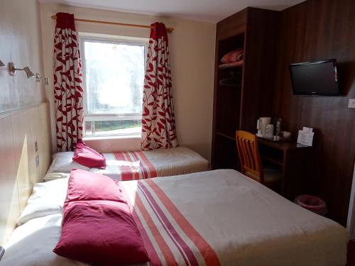 um quarto de hotel com duas camas e uma janela em The Gatwick White House Hotel em Horley