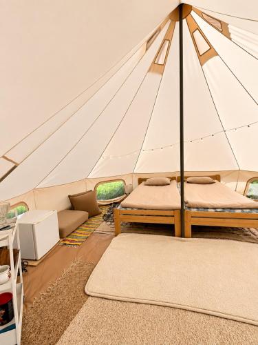 a tent with a bed and a couch in a room at Vallimäe Glamping Otepää in Mägestiku