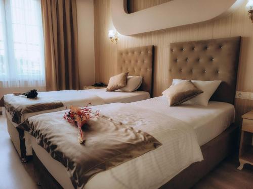 two beds in a hotel room with flowers on them at Grand Beyaz Saray Otel in Duzce